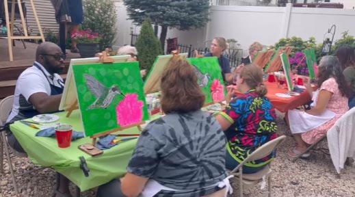 Group of painting students partake in the Flight of the Hummingbird paint and sip wine night art lesson taught by UW Madison alumni Louis Ely.